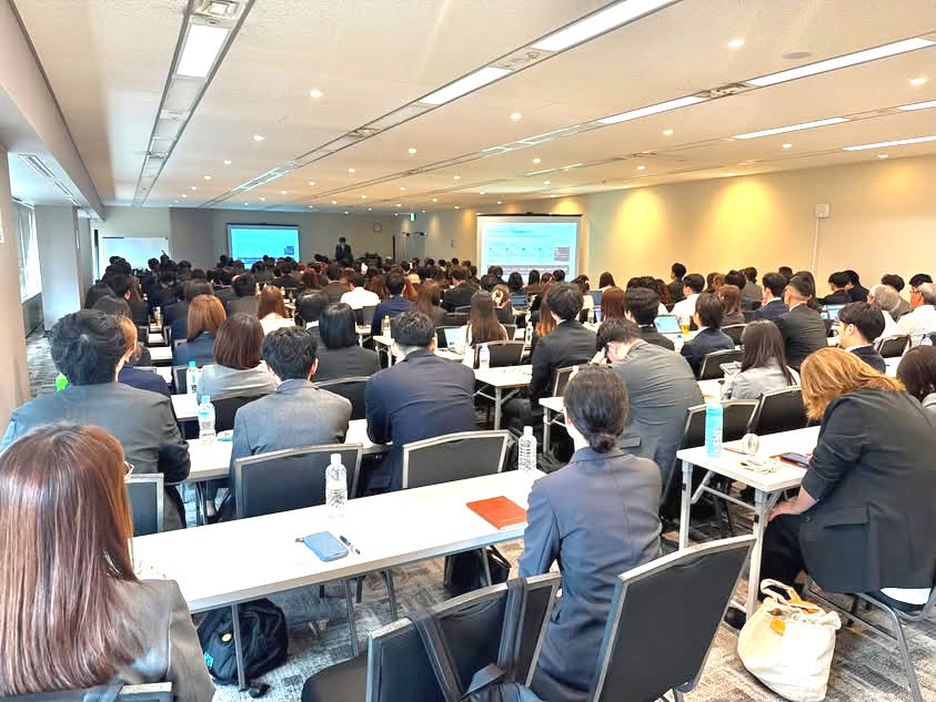 横濱コーポレーションの経営会議で発表者の話に真剣に耳を傾ける社員の様子。